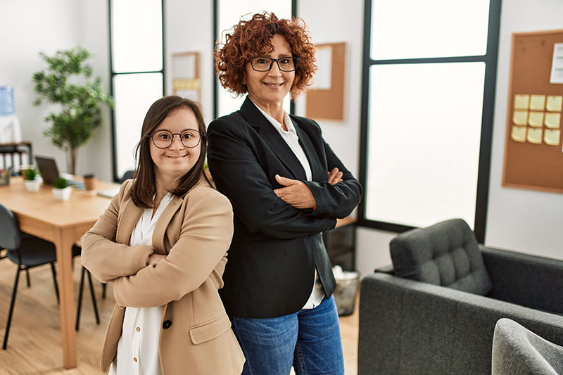 Two women posing together at an office environment
